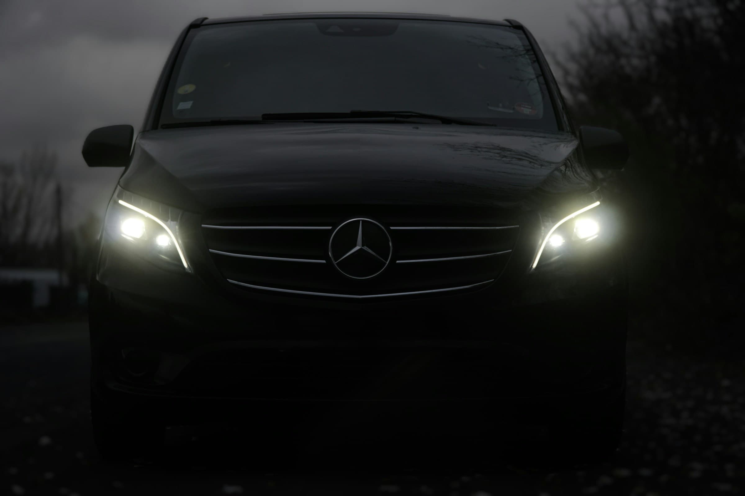 Mercedes-Benz V-Class chauffeur vehicle with headlights lit at dusk